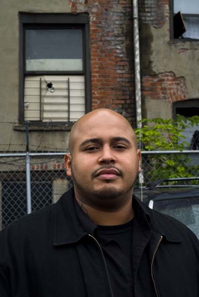 Cesar Guzman, 28, outside of the building where his family lives at 422 East 178th Street in the Bronx. The exterior is deteriorating, as well as the interior. Guzman blocked off the window, which was missing a pane.