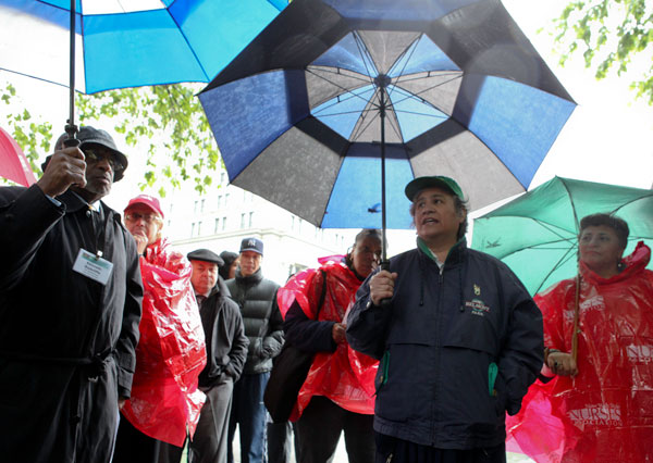 Judith Arroyo, president of local 436 (in blue jacket), speaks at a rally at City Hall to protest proposed cuts to the City's healthcare spending.