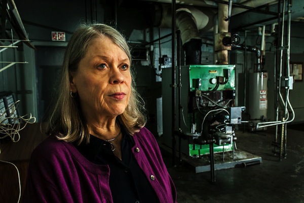 Susan Asis, supervisor of Brooklyn's New Lots branch library, with the building's  boiler. It's recently been repaired, but the fix is temporary; rust means the unit will break again.