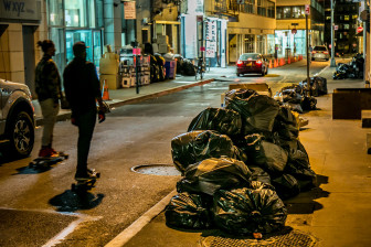 Skateboarders surfing southeast  on trash lined  Ann st in downtown Manhattan.