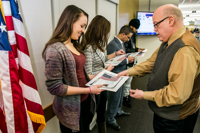  Supervisory Immigration Officer Joseph Mormino handing Sarah Siebes a certificate of citizenship as Sarah’s twin sister Emma Siebes,  Rashed Alhanshali and Dario Cruz look on.