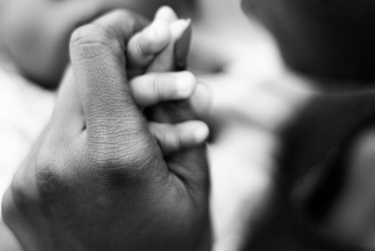 mother holds babys hand