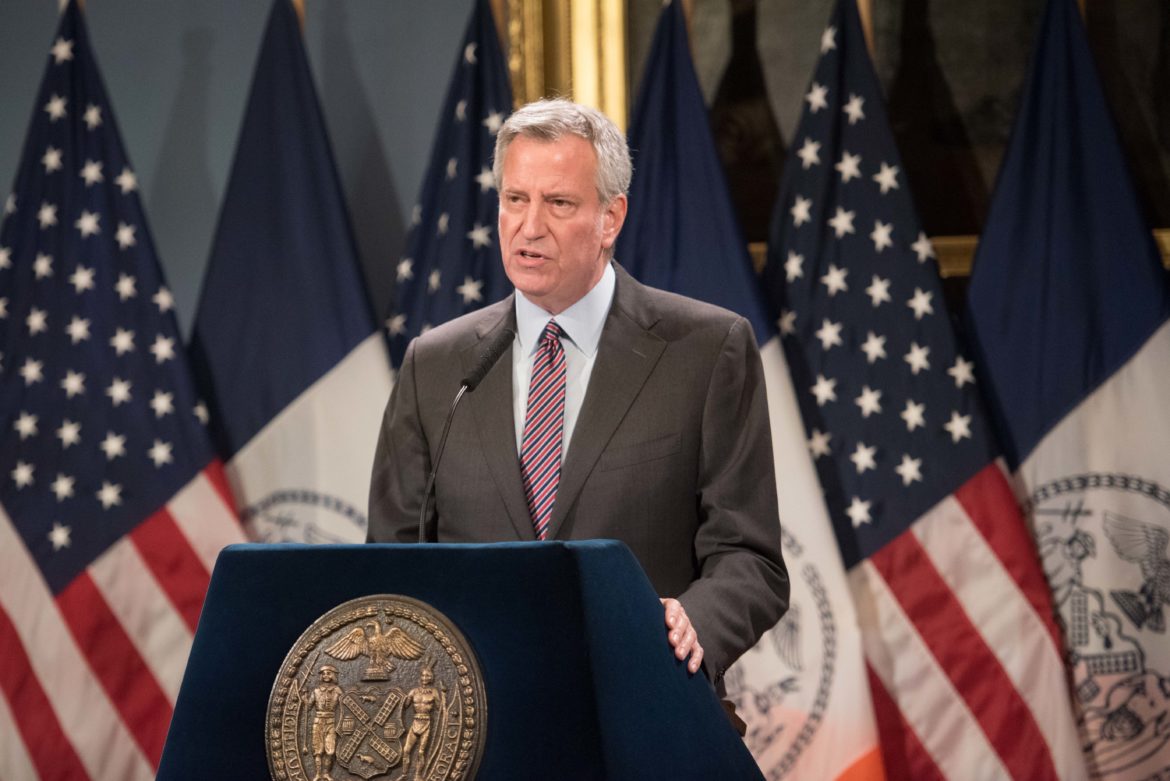 Former Mayor Bill de Blasio stands at podium