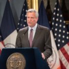 Former Mayor Bill de Blasio stands at podium