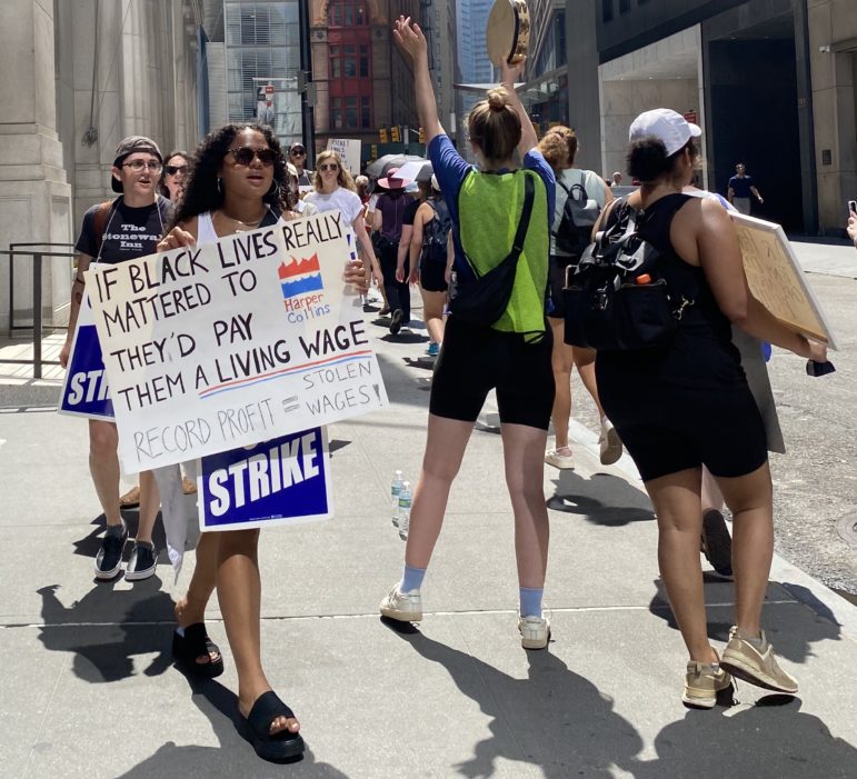 UAW Local 2110 picketers march around Dey Street during a strike against HarperCollins and one supporter raises a sign with the slogan “If Black lives really mattered, they’d pay them a living.”