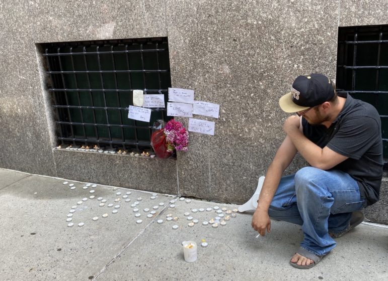 John Grima kneels near a memorial for a homeless friend who died in June.