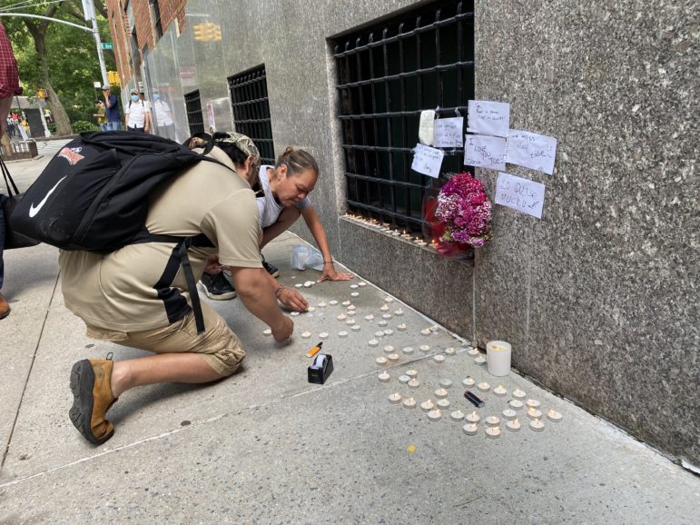 Mourners light candles at a street memorial