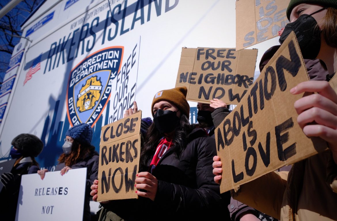 Protestors hold signs calling for the closure of Rikers Island jails