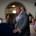 NYC Mayor Eric Adams talking into a microphone at a press conference podium